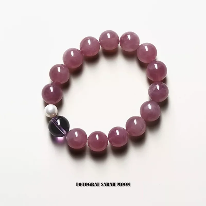 A pink strawberry quartz bracelet made with 10mm round beads, designed to attract love and amplify charisma. The bracelet is infused with Taoist energy and features a soft glow that symbolizes emotional balance and romantic energy.