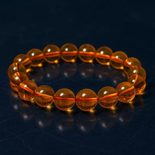 A honey-colored citrine bracelet placed on a dark slate background, representing grounding